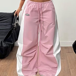 Peut inclure: Pantalon rose et blanc à blocs de couleurs avec une taille à cordon de serrage. Le pantalon a une coupe ample et ample et un petit écusson logo sur le devant. Le pantalon est en matière légère, adapté au port décontracté.