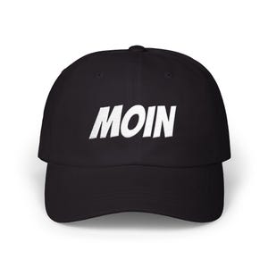 Könnte beinhalten: Eine schwarze Baseballkappe mit dem Wort MOIN, das in weißen Großbuchstaben auf die Vorderseite gestickt ist. Die Kappe hat eine strukturierte Krone, einen gebogenen Schirm und einen Knopf oben in der Mitte. Das Design ist mittig platziert.