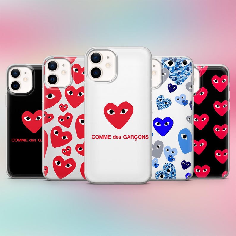 K&ouml;nnte beinhalten: Eine Auswahl an Handyh&uuml;llen mit Herzmotiven. Die H&uuml;llen zeigen ein rotes Herz mit Augen, einen wei&szlig;en Hintergrund und den Text "COMME des GAR&Ccedil;ONS". Andere H&uuml;llen haben Herzmuster in verschiedenen Farben.