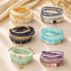 May include: Six sets of multi-layered stretch bracelets featuring various beads, including gold-tone metallic spheres, clear crystals, opaque white, navy blue, turquoise, mint green, and purple glass beads, with one charm engraved with the word Love.