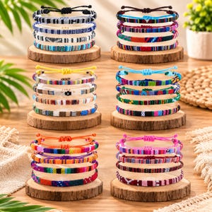 May include: Six stacks of woven friendship bracelets, each featuring adjustable sliding knots and diverse geometric patterns in vibrant color palettes including blue, yellow, orange, pink, red, and black, displayed on circular wooden bases.