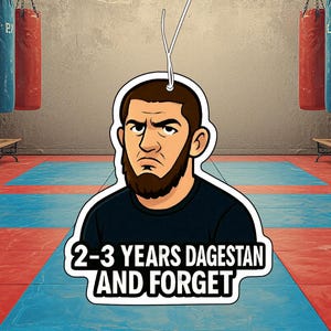 Könnte beinhalten: Ein hängender Lufterfrischer mit einer Cartoon-Illustration eines bärtigen Mannes in einem schwarzen T-Shirt. Der Text "2-3 YEARS DAGESTAN AND FORGET" ist in fetten schwarzen Buchstaben auf weißem Grund am unteren Rand abgebildet.