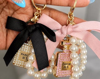 Colgante para bolso con forma de frasco de perfume, adornado con diamantes de imitación, perlas y lazo.