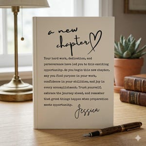 May include: A white rectangular card featuring the black text 'a new chapter' with a heart symbol. Below, a printed message reads: 'Your hard work, dedication, and perseverance have led you to this exciting opportunity.' The name 'Jessica' is at the bottom.