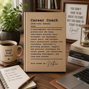 May include: A tan rectangular sign featuring a dictionary-style definition of Career Coach in black text, including the phonetic pronunciation, a detailed description of the role, and the name Nathan written in a cursive script at the bottom.