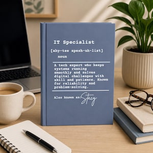 Puede incluir: Un cuaderno azul con el texto "IT Specialist" y una definición. La definición describe a un experto en TI que mantiene los sistemas funcionando sin problemas. El cuaderno también dice "Also known as Stacy".