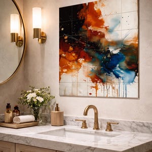May include: Abstract artwork on tiles, with a dynamic mix of colours. The piece features splashes of orange, blue, and white, creating a vibrant, modern aesthetic. It's mounted above a bathroom vanity, with a gold tap and mirror.