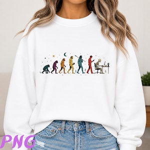 May include: A white crewneck sweatshirt featuring a colorful graphic print of human evolution. The design depicts the progression from a primate to a skeleton sitting at a desk with a computer, surrounded by small stars, a moon, and plant icons.