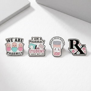 Op de afbeelding: Set van vier emaille pins met apotheek-thema ontwerpen. E&eacute;n pin leest "WE ARE PHARMILY", een andere zegt "I AM A PHARMACY STUDENT I HAVE NO LIFE", een derde zegt "LEGAL DRUG DEALER", en de laatste heeft een Rx-symbool met bloemen.