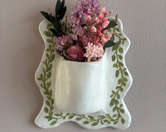 May include: A white ceramic mug with a black handle and the text "But First, Coffee" in a handwritten style. The mug is on a white surface. The mug is approximately 4 inches tall.