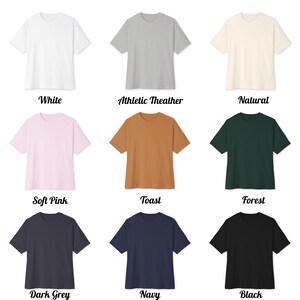 May include: Nine short-sleeved t-shirts in a range of colours: white, grey, natural, pink, brown, green, dark grey, navy, and black. Each shirt is shown with its colour name below in a decorative font.