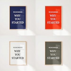May include: Four rectangular wall art prints in light wood frames, each featuring the white text REMEMBER WHY YOU STARTED. The backgrounds are solid navy blue, bright red, white, and dark gray, displayed in a grid on a plain white wall.