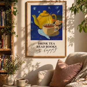 Peut inclure: Une affiche encadrée représentant une théière jaune, une tasse à thé et un cupcake sur fond bleu avec des étoiles. L'affiche contient le texte "DRINK TEA READ BOOKS Be happy" en écriture manuscrite. L'œuvre est exposée dans un salon confortable.