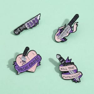 May include: Four enamel pins with knife designs. One pin reads "NOT YOUR BABE" with dripping purple accents. Another features a knife with "GOD'S MENU" on a flame design. A heart with "TRUE CRIME" and a knife. The last pin says "KILL THE PATRIARCHY".