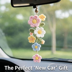 May include: A crochet floral car charm featuring a cascade of colorful flowers in pink, yellow, white, and blue. The charm hangs from a rearview mirror, adding a touch of handmade charm to the car's interior.