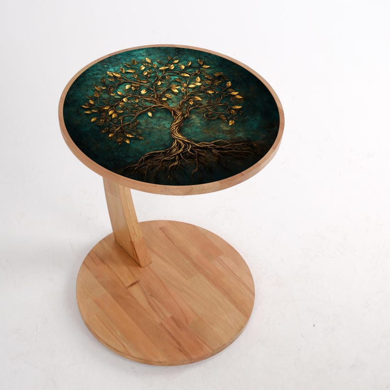 May include: A small, round side table with a wooden base and a tabletop featuring a detailed golden tree design against a teal background. The table has a single curved leg and a circular base, showcasing a natural wood finish.