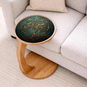 May include: A round side table with a wooden frame and a teal and gold tree of life design on the tabletop. The table has a curved leg and is placed next to a light gray sofa.