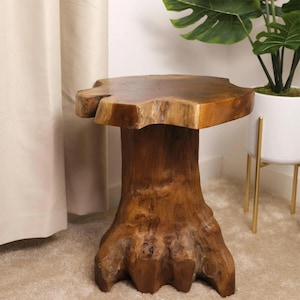 May include: A natural wood side table with a unique tree stump design. The table features a thick, irregular top and a sturdy base resembling tree roots. The wood has a warm, brown tone, adding a rustic and organic feel to any space.