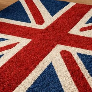Puede incluir: Una alfombra rectangular con el dise&ntilde;o de la bandera de la Union Jack. La alfombra tiene un fondo azul con una cruz roja y rayas diagonales blancas. La alfombra est&aacute; hecha de un material suave y texturizado.