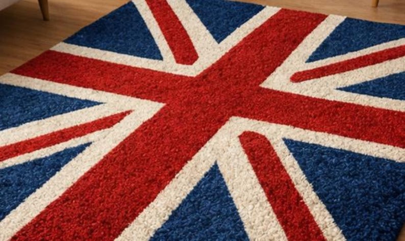 Puede incluir: Una alfombra rectangular con el dise&ntilde;o de la bandera de la Union Jack. La alfombra tiene un fondo azul con una cruz roja y rayas diagonales blancas. La alfombra est&aacute; hecha de un material suave y texturizado.