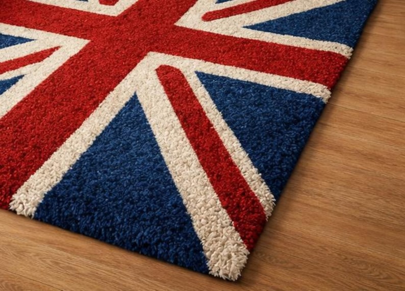 Puede incluir: Una alfombra rectangular con el dise&ntilde;o de la bandera brit&aacute;nica, la Union Jack. La alfombra tiene un fondo azul con rayas rojas y blancas, con una textura visible. Colocada sobre un suelo de madera.