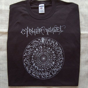 May include: Black t-shirt with a white graphic of a cipher wheel and the text "Cipher Wheel".