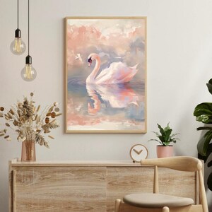 Peut inclure: Une impression d'art encadrée représente un cygne blanc glissant sur l'eau, avec un fond de ciel rose et bleu. L'œuvre est dans un cadre en bois, créant une esthétique sereine et élégante. Le reflet du cygne est visible dans l'eau.