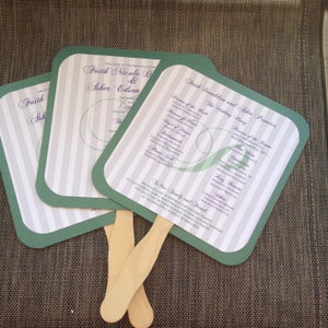 May include: Three green and white wedding fans with a striped pattern and purple text. The fans are folded and have wooden handles. The text on the fans includes the names of the bride and groom, the wedding party, and the order of the ceremony.