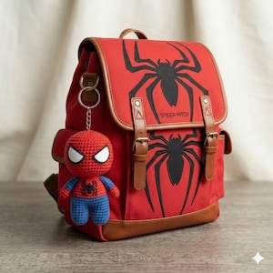 May include: A red canvas backpack with brown faux leather trim, featuring a black spider graphic and the text "SPIDER-HITCH" on the front flap. The bag includes two vertical buckle straps and a crocheted red and blue spider-themed keychain.