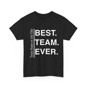 Op de afbeelding: Een zwart t-shirt met korte mouwen en witte tekst die BEST. TEAM. EVER. leest in een gestapelde lay-out. Links van de hoofdtekst scheidt een verticale lijn de zin van de kleinere verticale witte tekst die Team Name or Job Title leest.
