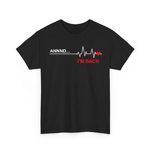 Puede incluir: Camiseta negra con el texto "ANNNND... I'M BACK" en blanco y rojo. El diseño incluye una línea de latido cardíaco con un corazón rojo. Una camiseta gráfica sencilla pero audaz.