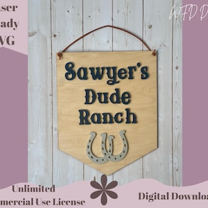 May include: Wooden sign with the text "Sawyer's Dude Ranch" in dark letters, featuring two silver horseshoes. The sign is laser-ready and includes a leather hanging strap. The sign is a digital download.