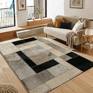May include: A rectangular area rug with a patchwork design. The rug features a geometric pattern of various neutral colors, including black, gray, and beige. The rug is made of a soft, textured material and is suitable for a living room or bedroom.