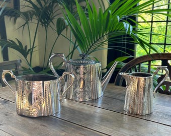 Juego de té antiguo de 3 piezas chapado en plata, tetera y cubertería decorativa.
