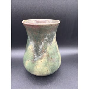 May include: A ceramic vase with a flared rim and a rounded body. The surface features a mottled glaze with blended tones of sage green, earthy brown, and hints of deep red, creating a textured appearance with subtle white speckling throughout.