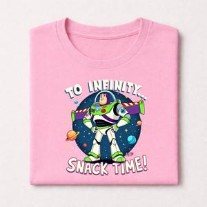 Peut inclure: T-shirt rose clair avec un dessin de Buzz l'&Eacute;clair de Toy Story. Le motif comprend le texte "TO INFINITY... SNACK TIME !" Buzz est repr&eacute;sent&eacute; dans sa combinaison spatiale blanche, verte et violette, sur fond &eacute;toil&eacute;.