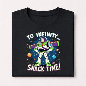 Peut inclure: T-shirt noir avec une illustration de Buzz l'&Eacute;clair de Toy Story. Le personnage est entour&eacute; d'un fond spatial avec des plan&egrave;tes et des &eacute;toiles. Le texte sur le t-shirt dit "TO INFINITY... AND SNACK TIME!"