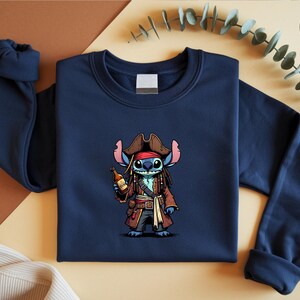 May include: Navy blue sweatshirt featuring a cartoon illustration of Stitch dressed as a pirate, complete with a brown hat, coat, and a bottle. The design is centered on the front of the crewneck sweatshirt.