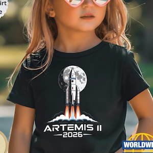 Może przedstawiać: Biały ceramiczny kubek z czarnym uchem i napisem "But First, Coffee" w stylu odręcznym. Kubek stoi na białej powierzchni. Kubek ma 10 cm wysokości.