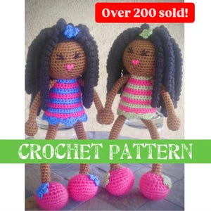 May include: Two handmade crochet dolls with dark hair and brown skin, wearing striped dresses in pink and blue or pink and green. The dolls have pink feet and the text "CROCHET PATTERN" is displayed.