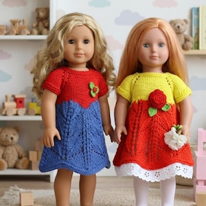 May include: Two dolls wearing handmade knit dresses. One dress is red and blue with a green flower accent, the other is yellow and red with a red rose accent. Both dresses have short sleeves and are knee-length.