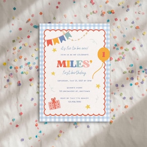 May include: A rectangular birthday invitation card with a light blue gingham border and a scalloped red edge. The text reads: it's fun to be one! JOIN US AS WE CELEBRATE MILES' first birthday SATURDAY, JULY 21, 2027 AT 2PM QUINN'S HOME 123 ANYWHERE AT, ANYTOWN RSVP BY JULY 1 TO ASHLEY 123.456.7890. Features include colorful bunting, yellow stars, a gift box, and an orange balloon with the number 1.