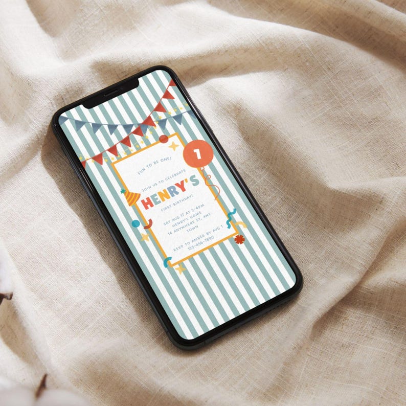 May include: A smartphone displays a birthday invitation with a striped background. The invitation features the text "HENRY'S FIRST BIRTHDAY" in colorful letters, along with party decorations and the number "1". The phone is black and rests on a beige fabric.