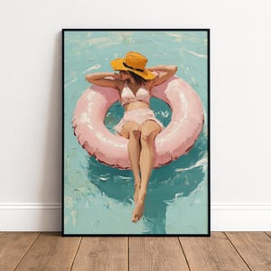 May include: A framed wall art print depicting an oil painting of a figure wearing a light pink two-piece swimsuit and a bright yellow sun hat, floating in a large pink inflatable pool ring on turquoise water with visible brushstroke textures.