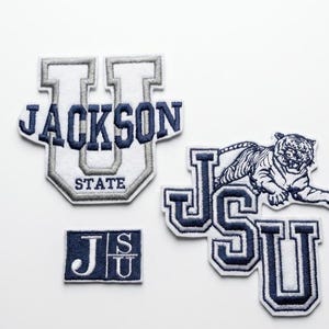 以下が含まれることがあります： ネイビーブルーと白の刺繍パッチ。「JACKSON STATE」と「JSU」の文字入り。1つのパッチには虎のグラフィック。様々な形とサイズのパッチで、衣類やアクセサリーに最適です。