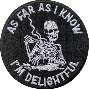 May include: Circular black patch with white embroidered text and a skeleton design. The text says "AS FAR AS I KNOW I'M DELIGHTFUL". The skeleton is depicted holding a cup with steam rising.