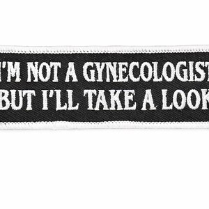 Può includere: Una toppa rettangolare in bianco e nero con la scritta "I'M NOT A GYNECOLOGIST BUT I'LL TAKE A LOOK" in bianco, ricamata. La toppa ha un bordo bianco ed è probabilmente progettata per essere cucita su abiti o accessori.