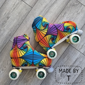 May include: Pair of roller skates with vibrant, geometric patterned covers in red, orange, yellow, green, blue, and purple. The skates have white wheels with green accents and grey stoppers. The text "MADE BY T" is in the bottom right corner.