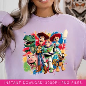 May include: A light purple sweatshirt featuring a colorful graphic of characters from the animated movie Toy Story. The graphic includes Woody, Buzz Lightyear, Rex, Jessie, Hamm, and Slinky Dog. The text "INSTANT DOWLOAD-300DPI-PNG FILES" is at the bottom.