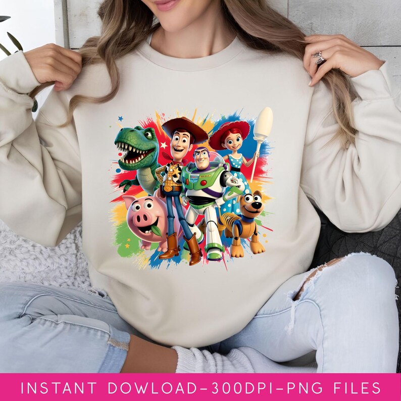 May include: A beige sweatshirt featuring a colorful graphic of characters from the Toy Story movie franchise. The design includes Woody, Buzz Lightyear, Rex, and other characters. The text "INSTANT DOWLOAD-300DPI-PNG FILES" is at the bottom.